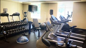 Un gimnasio con equipo de ejercicio, incluyendo mancuernas, una cinta de correr y una bicicleta estática.