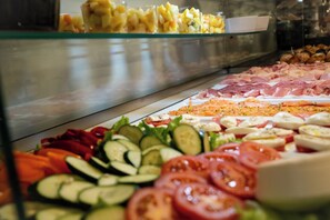 A buffet with various food items including sliced cucumbers, tomatoes, and a selection of meats.