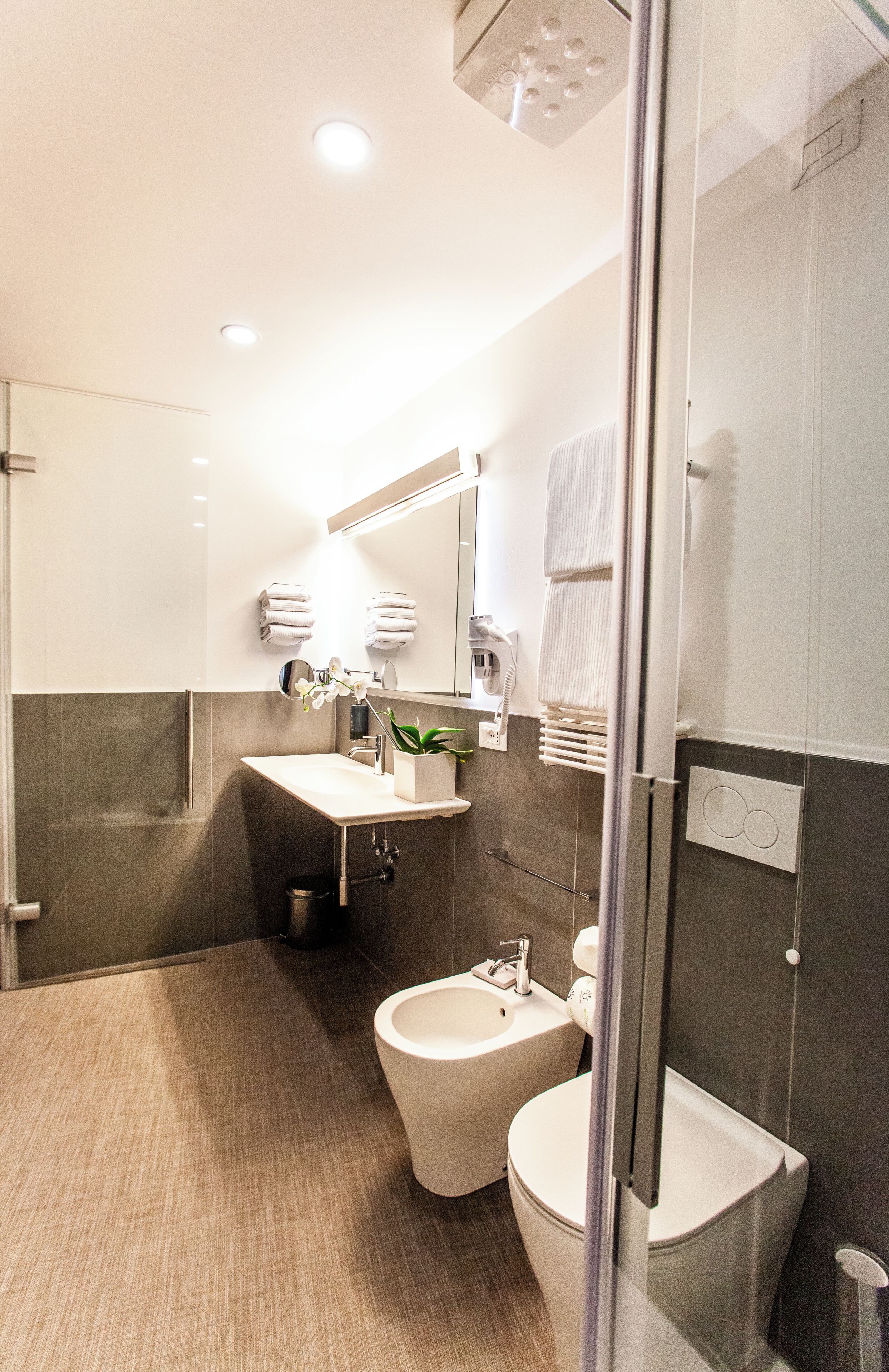 Une salle de bain moderne avec une douche à parois de verre, un lavabo avec un miroir et des toilettes.