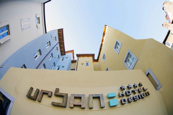 A hotel sign with "URBAN HOTEL DESIGN" and a modern building facade with multiple windows and balconies.