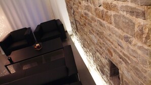 A modern room with a stone wall, black leather sofas, and a glass coffee table. - Urban Hotel Design (Trieste)
