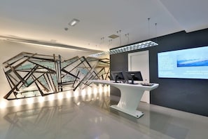 A modern reception area with a glass art installation, a reception desk, and a digital display.
