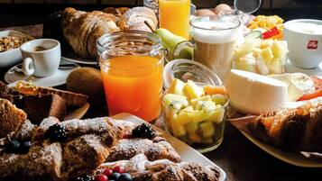 Un bufé de desayuno con diversos pasteles, frutas y bebidas.