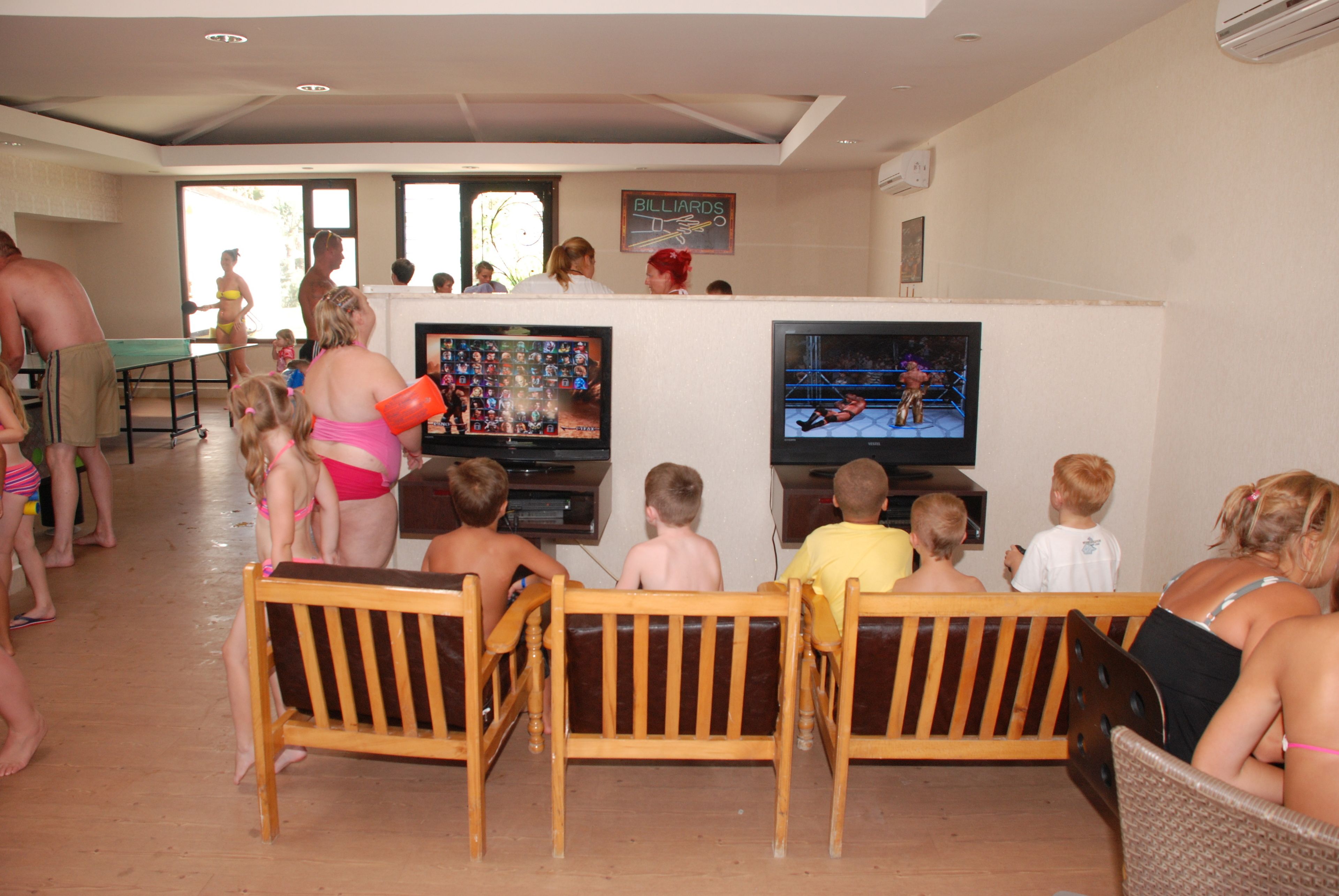 A room with wooden benches and a television displaying a boxing match.