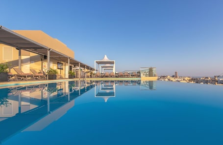 Una piscina techada, una piscina al aire libre, sombrillas