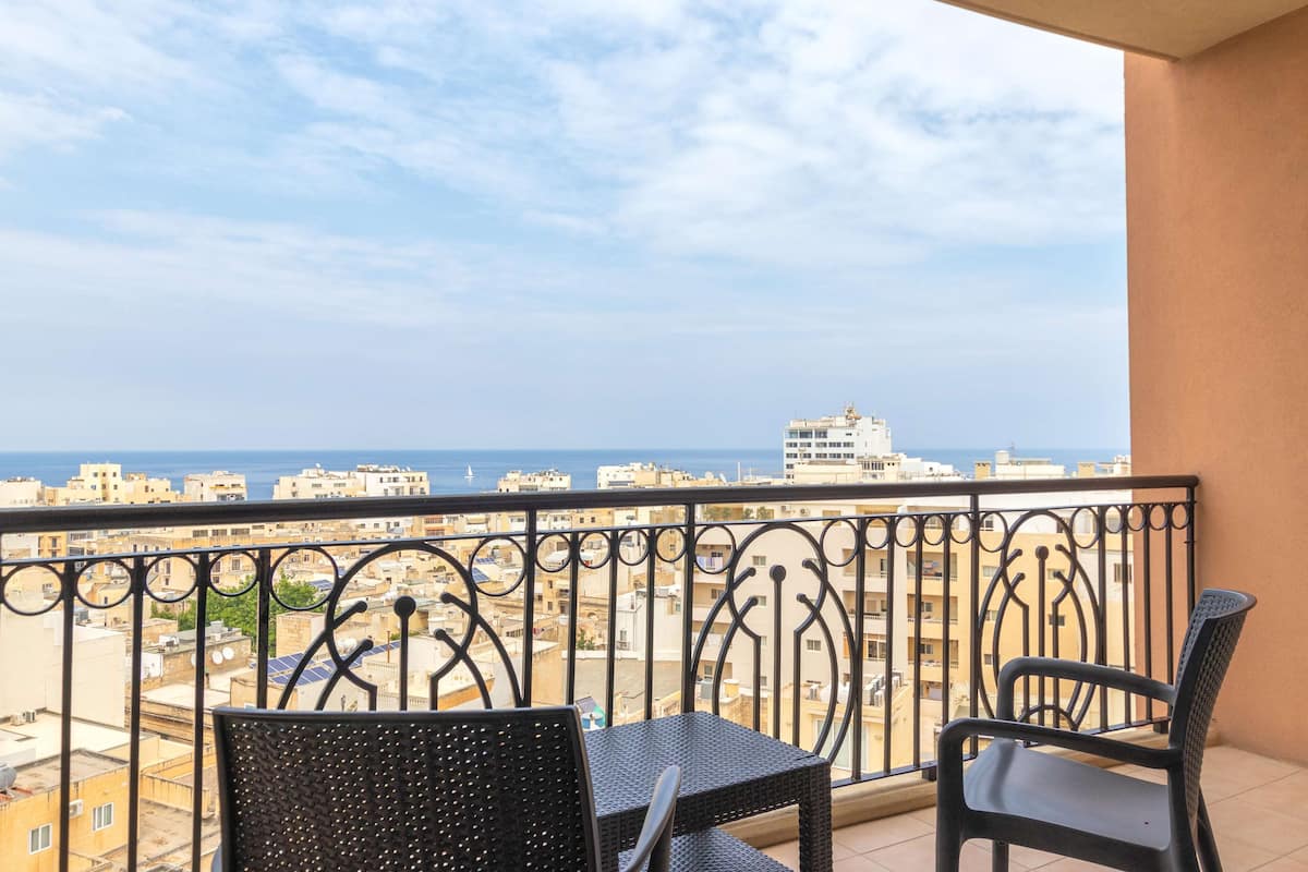A balcony with a view of the city and the sea.