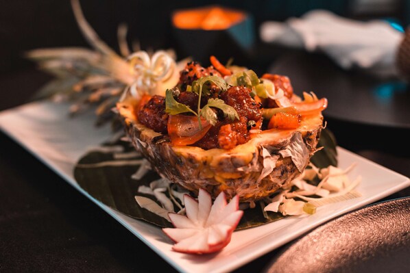 A dish with a unique presentation, possibly a seafood or meat-based dish, garnished with herbs and vegetables, served on a plate with a decorative leaf and a slice of radish.