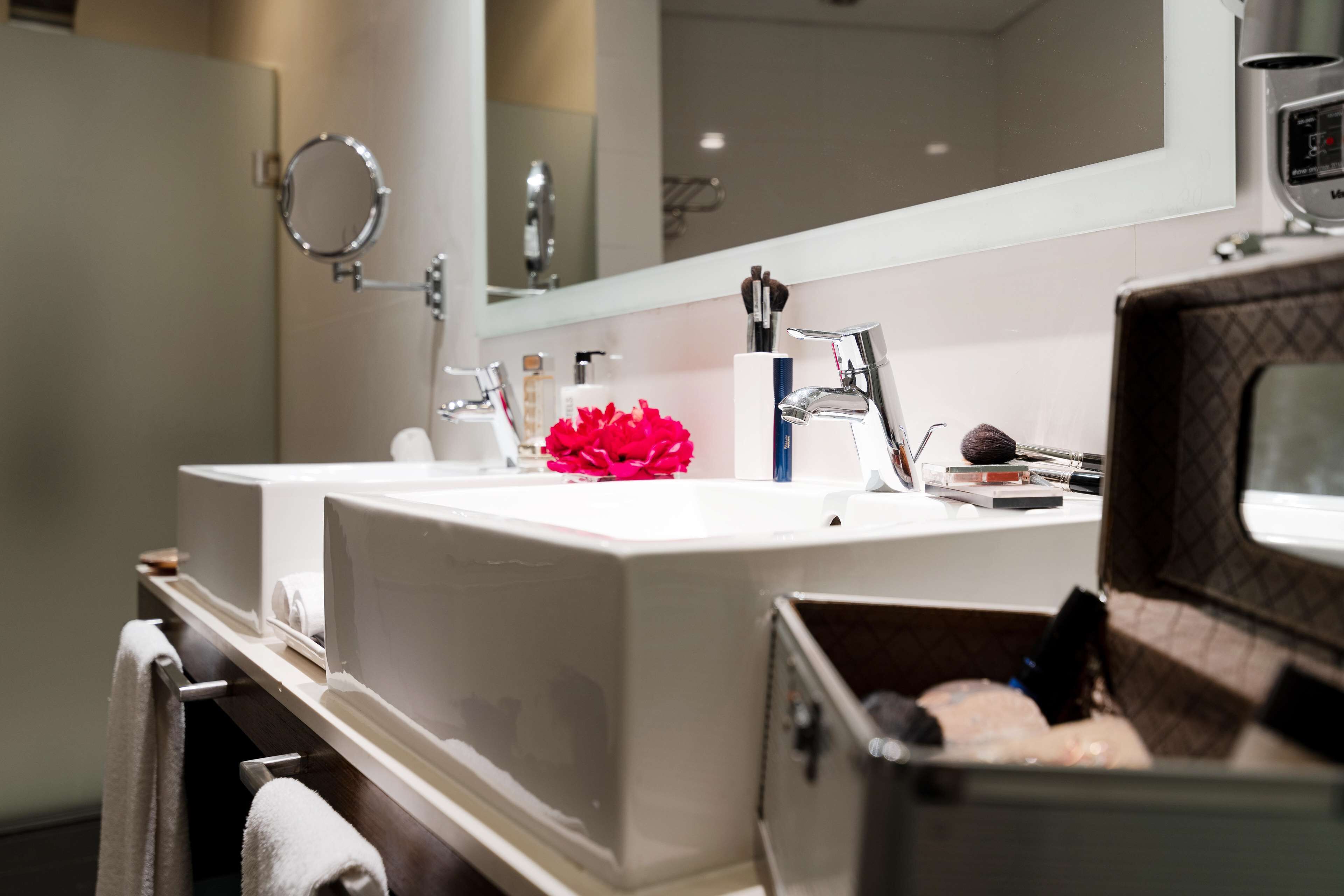 A modern bathroom with two sinks, a large mirror, and a vanity with toiletries.