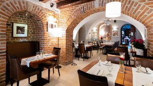 A restaurant with brick arches, wooden beams, and tables set for dining. - Hotel Rubinstein (Kraków)