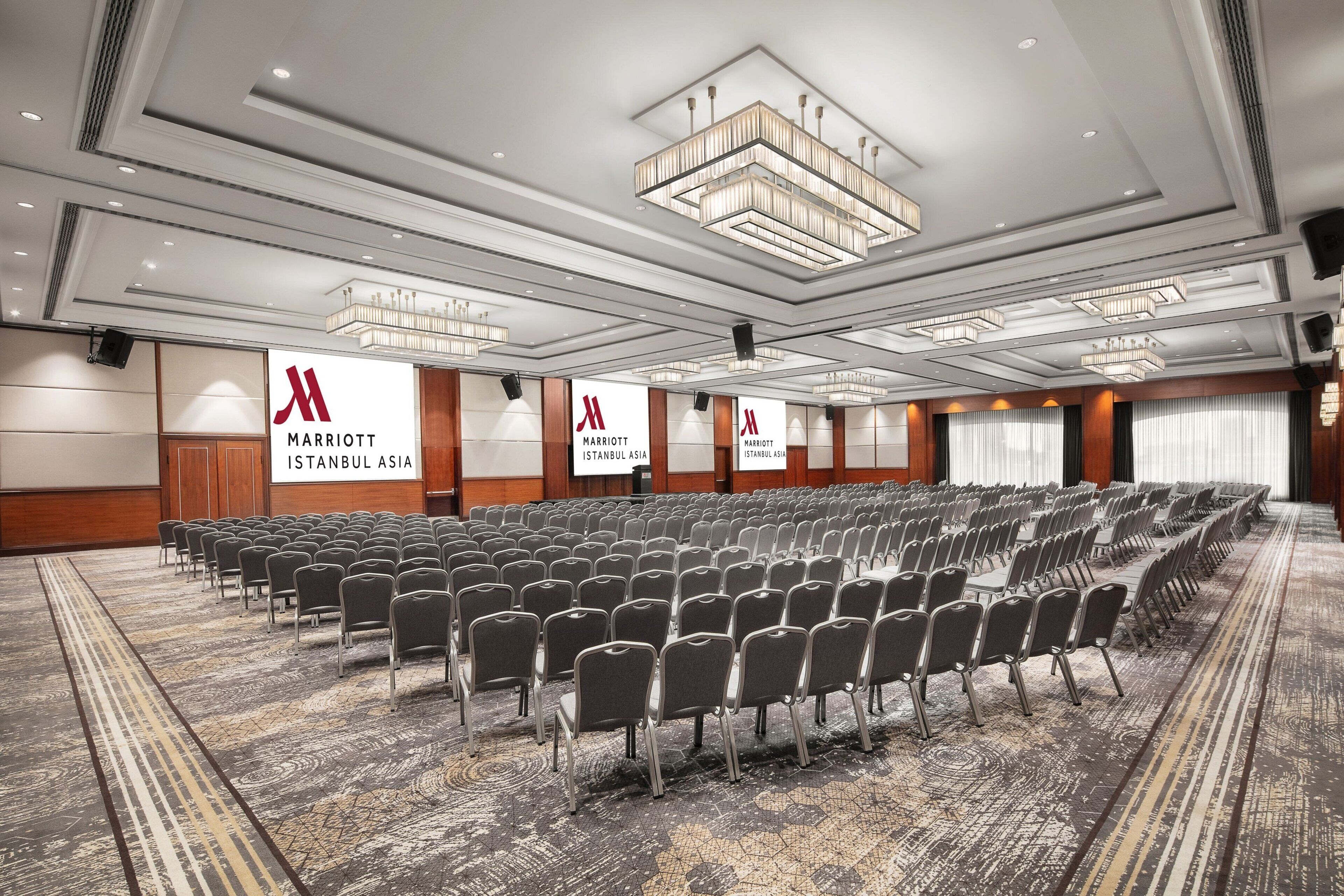 A large conference room with rows of chairs, a carpeted floor, and a chandelier.