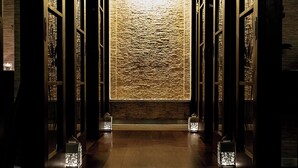 A hallway with wooden floors and walls, leading to a textured wall.