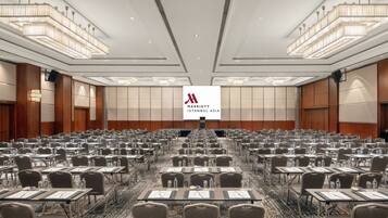 Ein großer Konferenzraum mit Tischen und Stühlen in Reihen, einem zentralen Bildschirm, der das Logo des Marriott Istanbul Asia zeigt, und einer modernen Kristallleuchter.