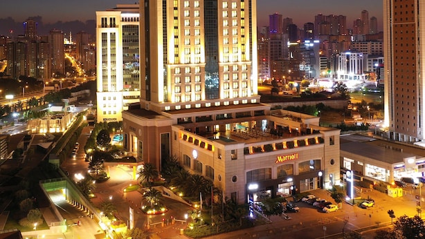 A Marriott hotel with a prominent central tower, multiple smaller buildings, and a well-lit parking area.