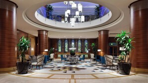 A spacious lobby with a central seating area, large columns, and a glass ceiling.