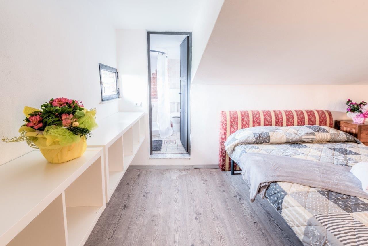 A bedroom with a bed, a nightstand, a window, and a door leading to a bathroom.