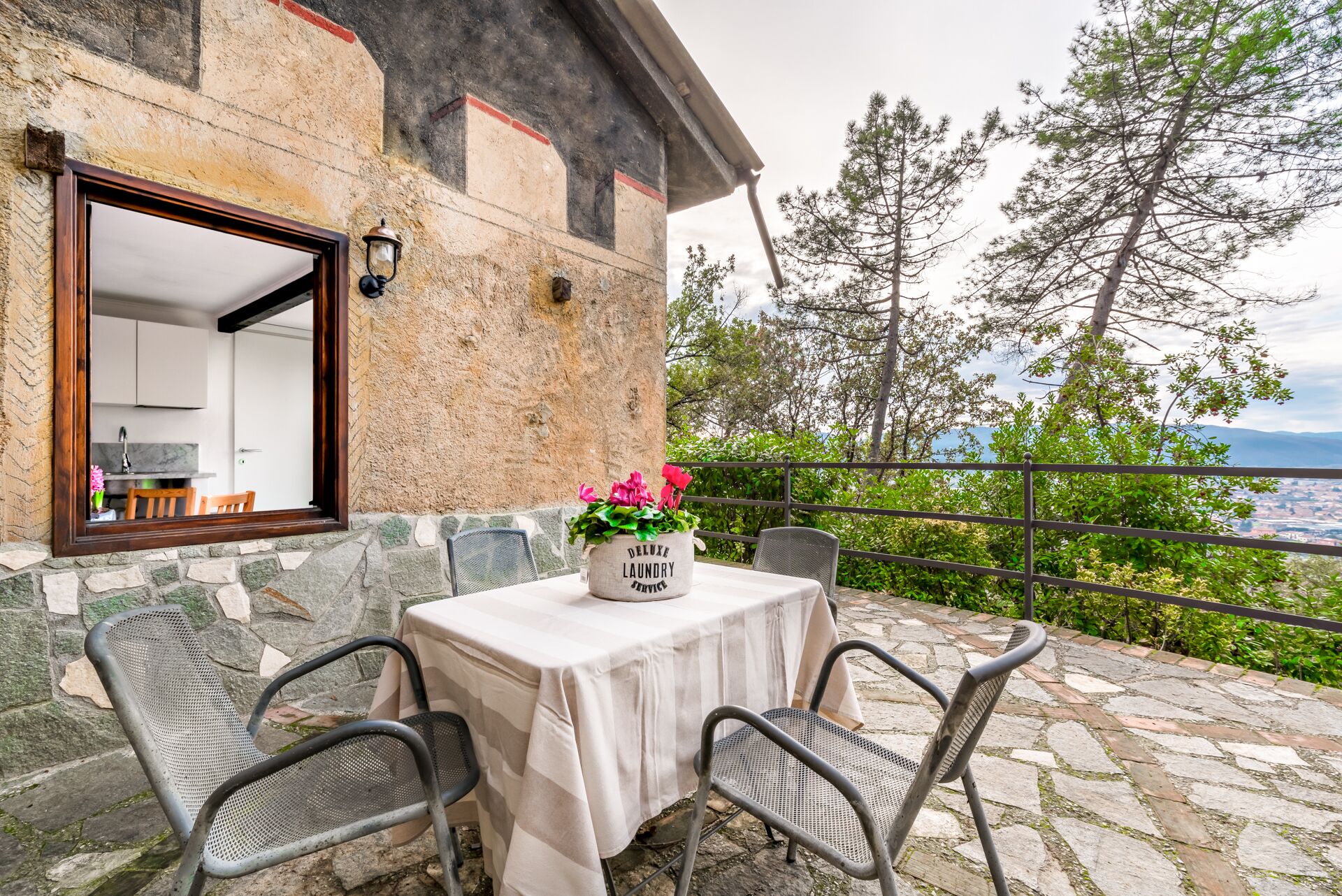 Eine Terrasse im Freien mit Tisch, Stühlen, einer Topfpflanze und Blick auf die Landschaft.