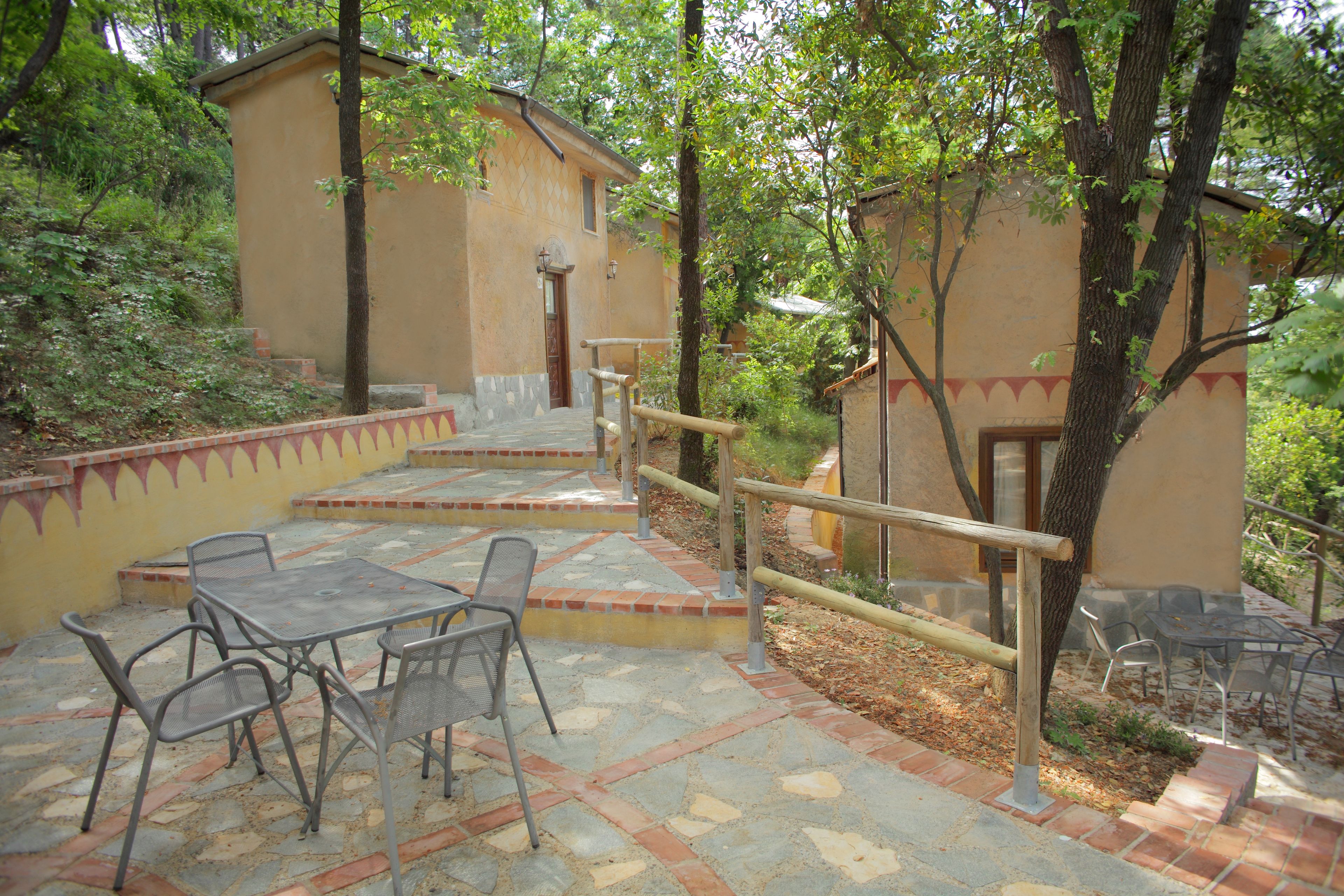 Un patio con mesa y sillas, baranda de madera y un edificio con puerta y ventanas.