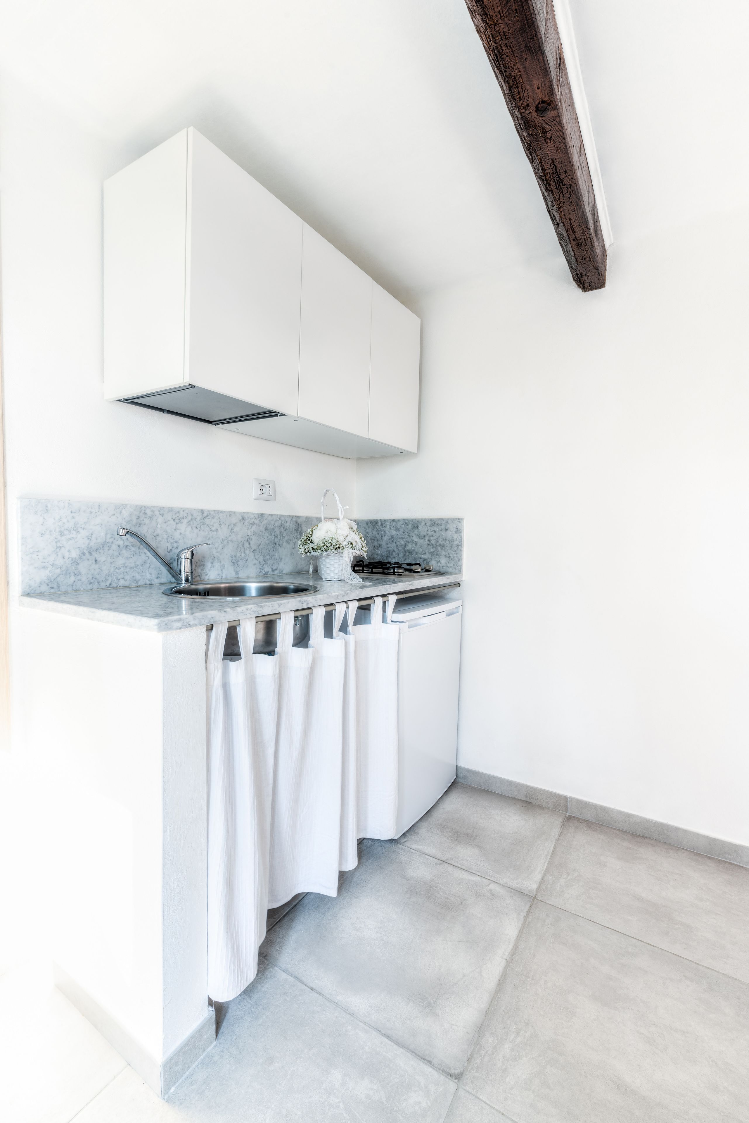 A modern kitchen with white cabinets, a marble countertop, and a built-in dishwasher.