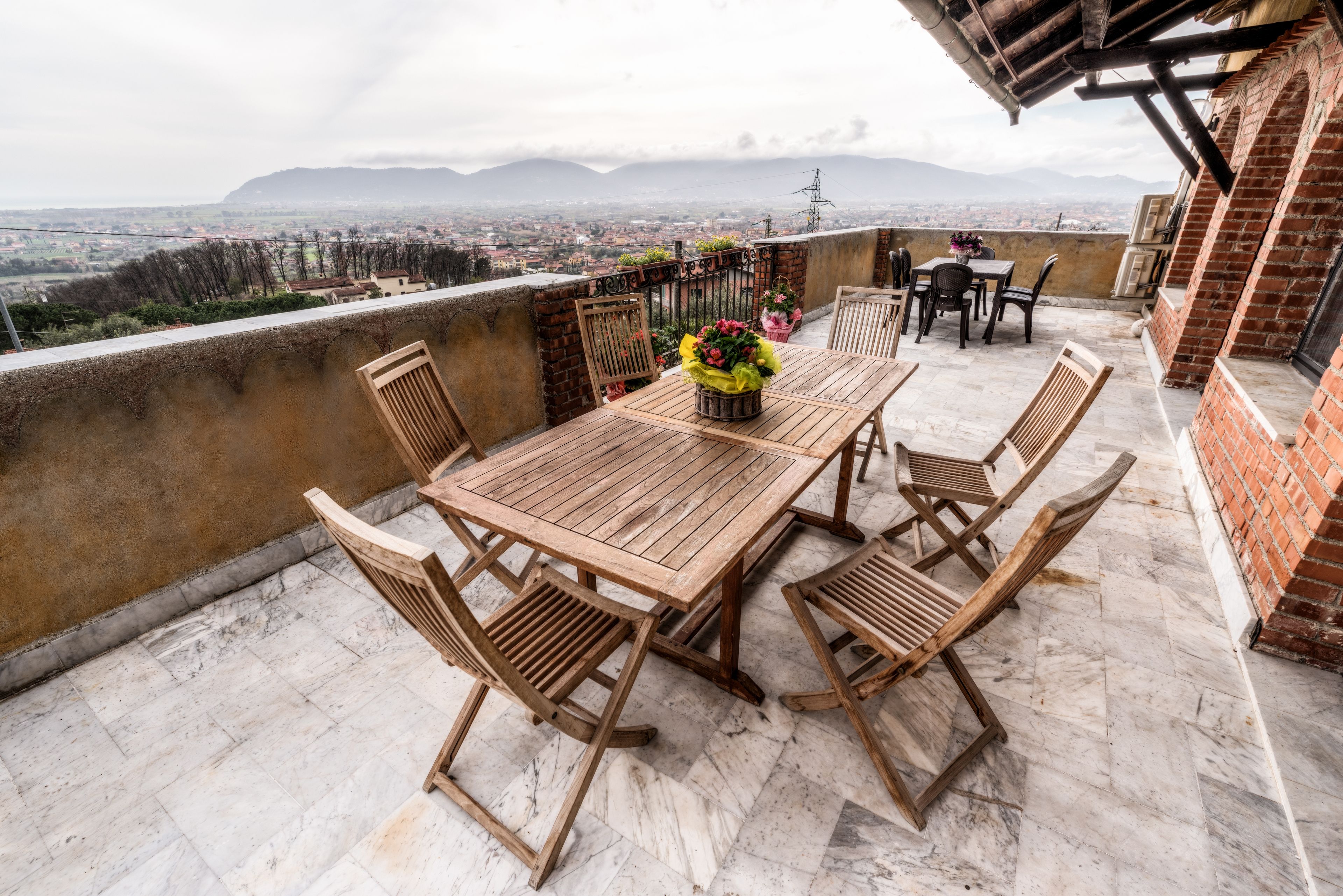 A wooden table and chairs on a terrace with a city view.