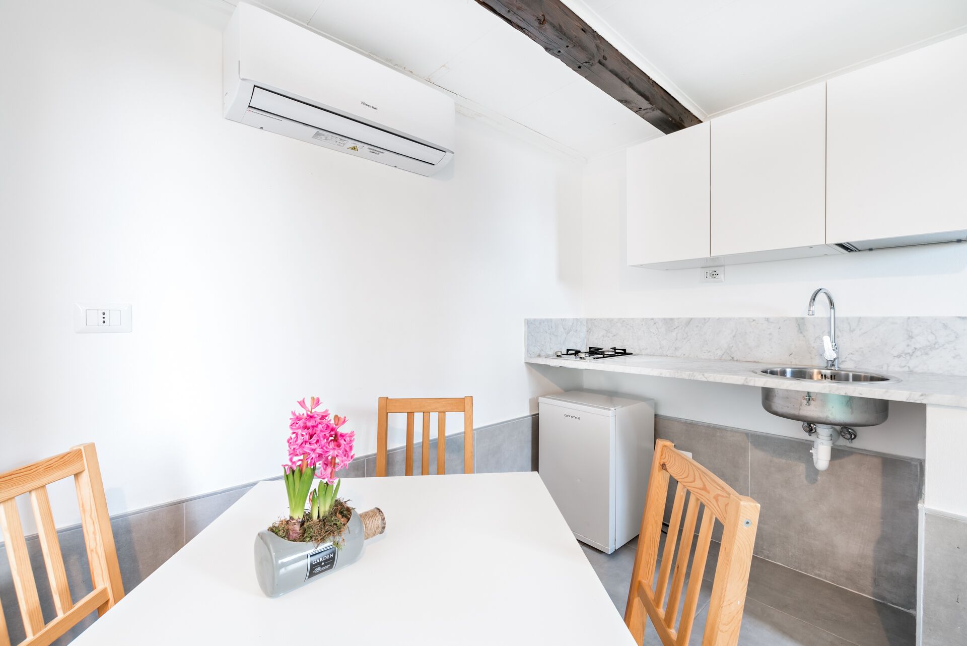 A modern kitchen with white cabinetry, a built-in sink, and a compact refrigerator.