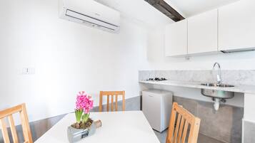 A modern kitchen with white cabinetry, a built-in sink, and a compact refrigerator.