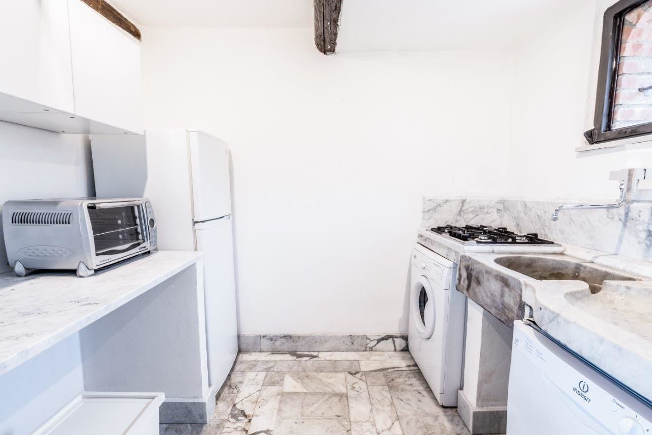 Eine kompakte Küche mit integrierter Waschmaschine, einem Gasherd und einem Toaster.