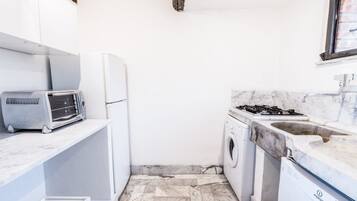 Eine kompakte Küche mit integrierter Waschmaschine, einem Gasherd und einem Toaster.