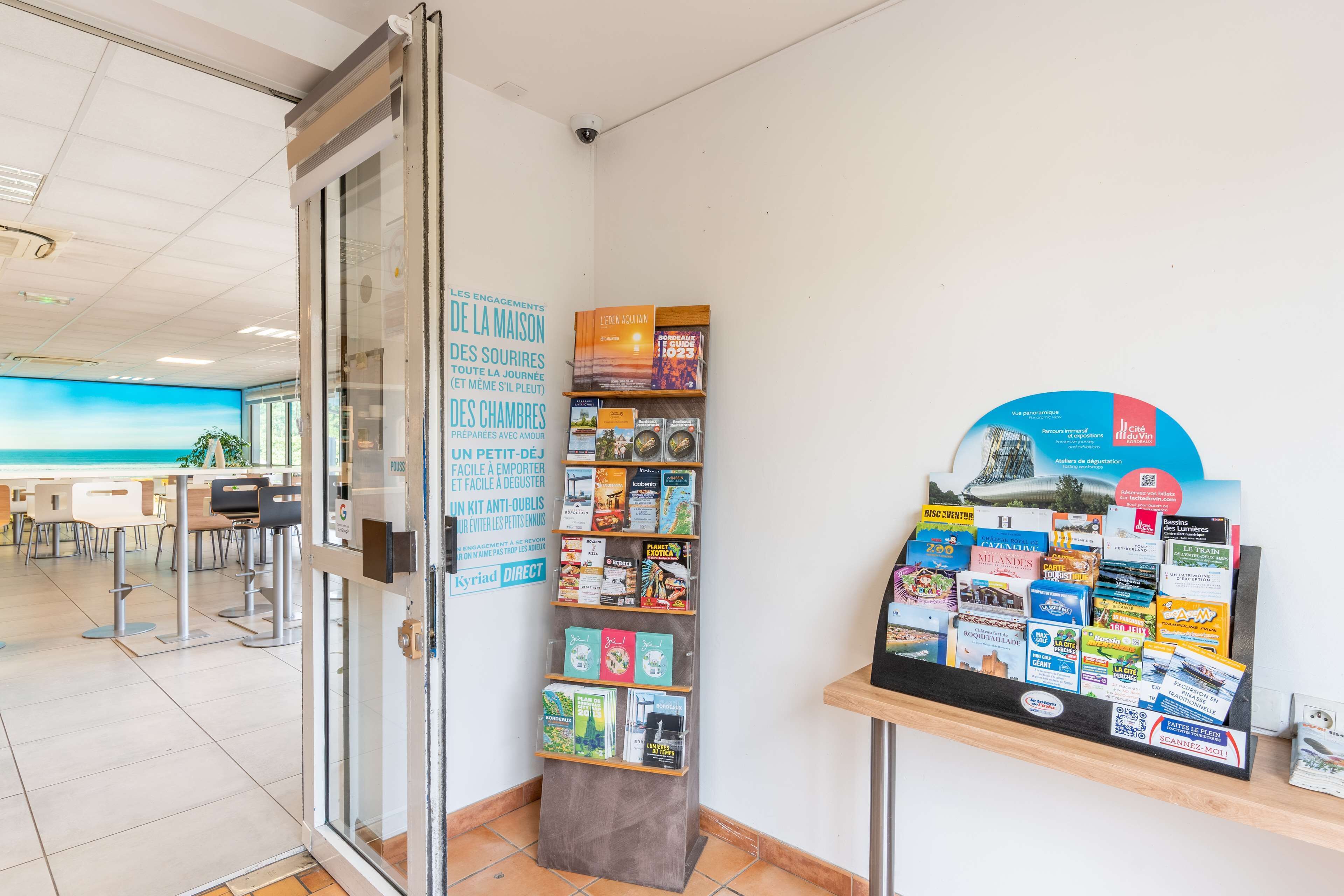 A reception area with a glass door, a bulletin board with various brochures, and a seating area with chairs and tables.