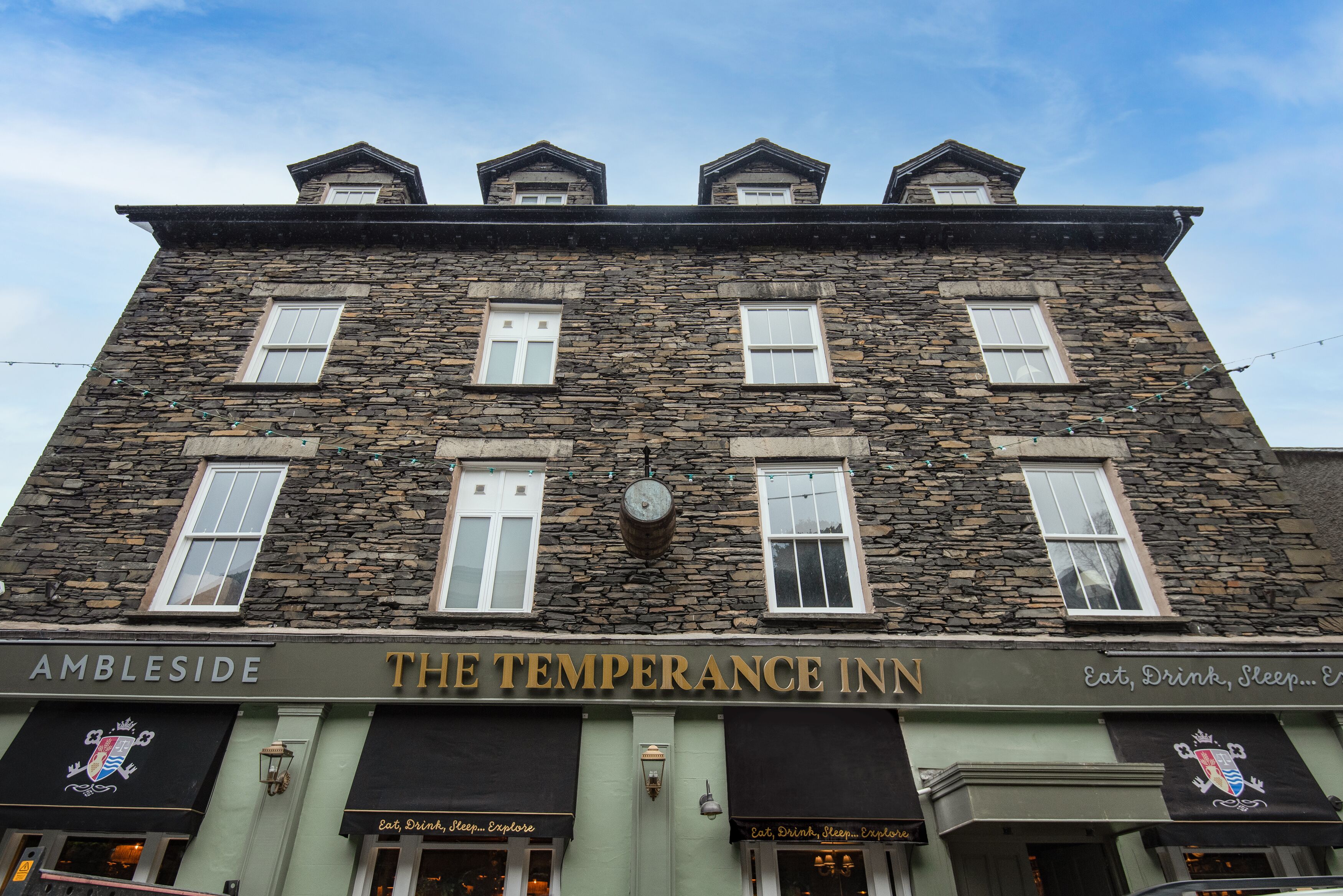 A stone building with the sign "The Temperance Inn" and "Ambleside" on the ground floor.