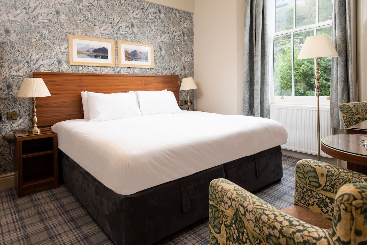 A neatly made bed with white linens, a wooden headboard, and two bedside lamps. There are two framed pictures on the wall above the bed.