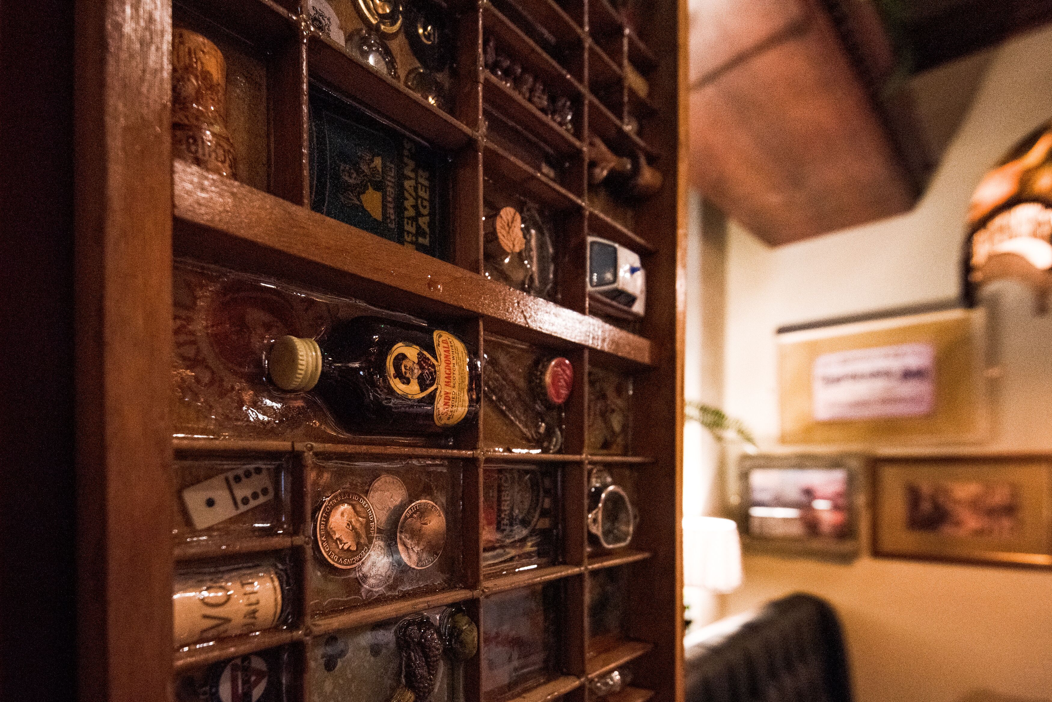A wall of vintage beer bottles and glasses in a dimly lit room.