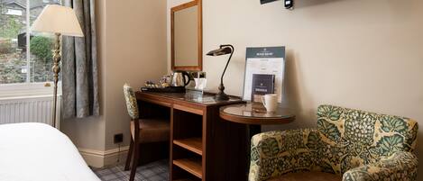 Een hotelkamer met een bed, een bureau met een lamp, een stoel, een televisie en een menubord.