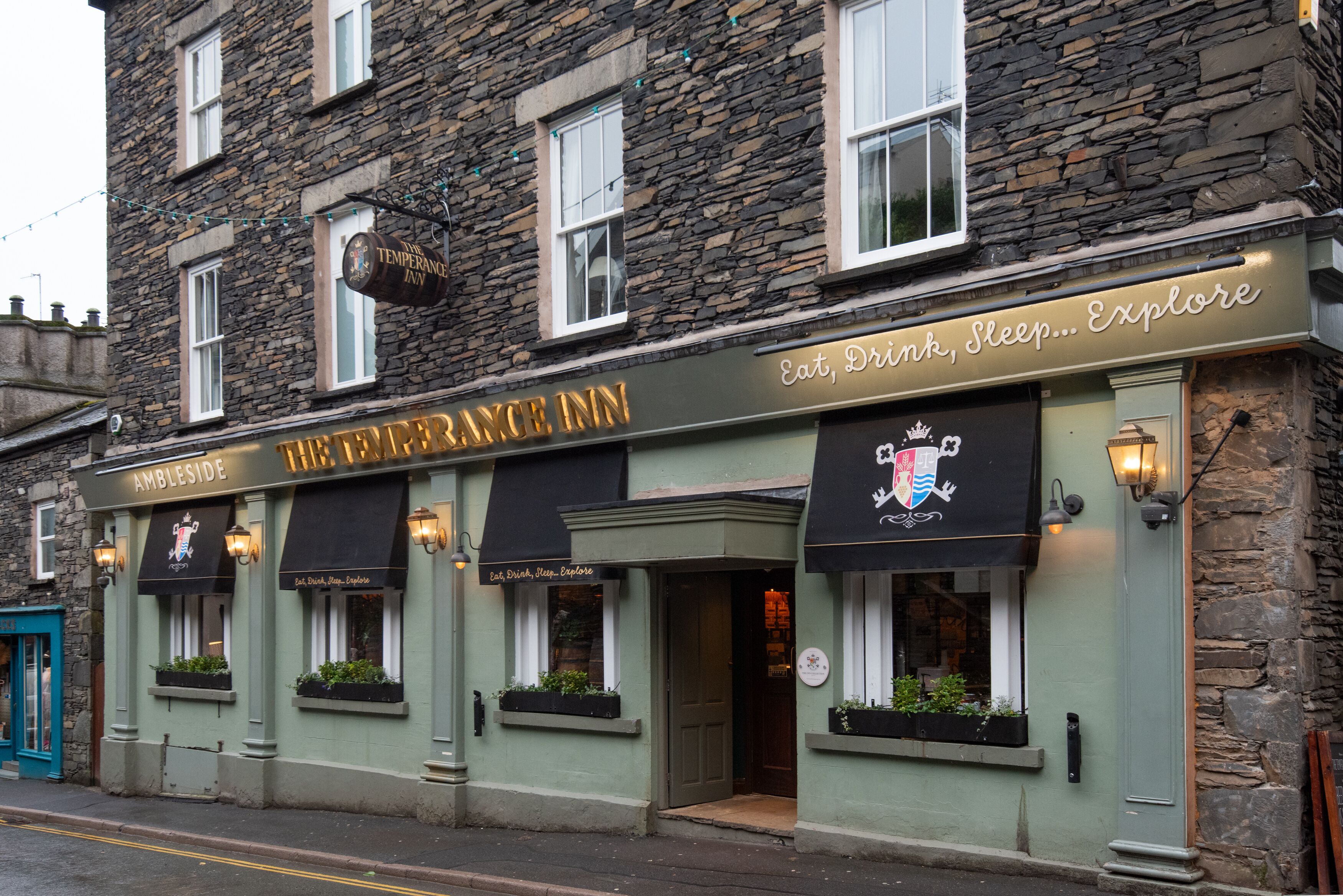 Le Temperance Inn se distingue par sa façade en pierre, ses auvents noirs et ses espaces de restauration en plein air agrémentés de jardinières.