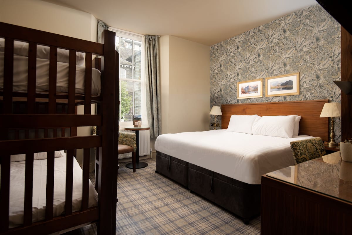 A bedroom with a large bed, a wooden headboard, a small table, and a chair.