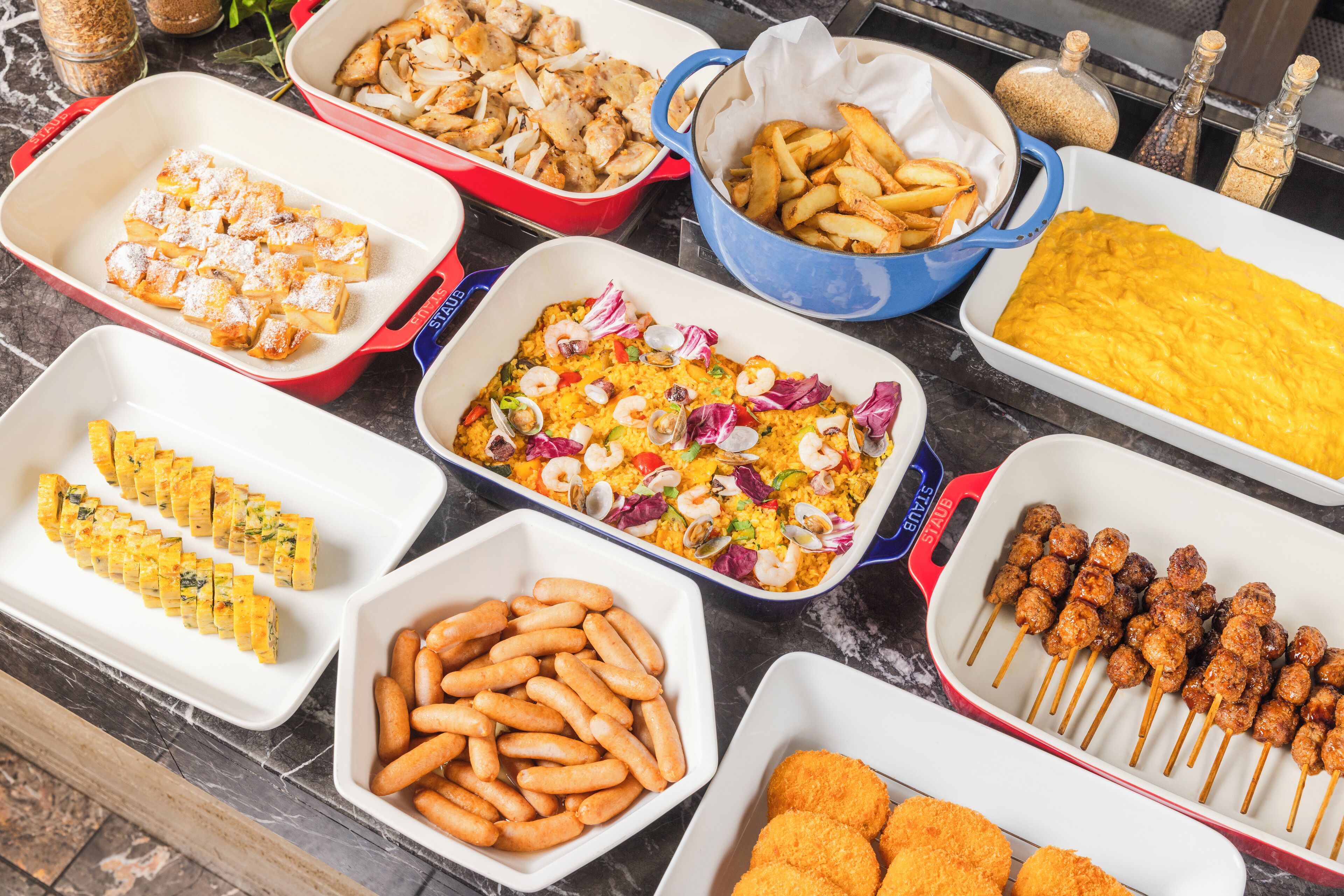 A variety of dishes including fried items, skewers, and a casserole.