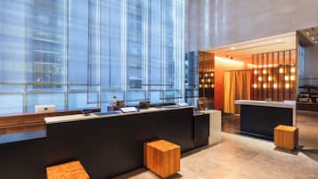 A modern reception area with a large glass window, a reception desk, and two wooden stools.