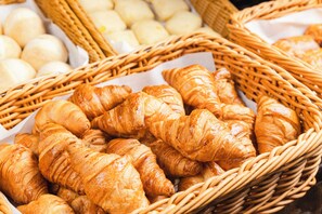Een mand vol warme, goudbruine croissants en ronde, witte gebakjes.
