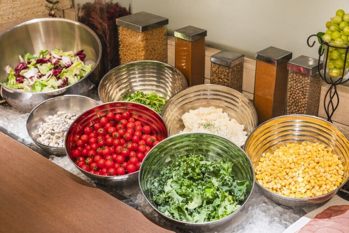 A variety of food items in metal bowls on a marble countertop.