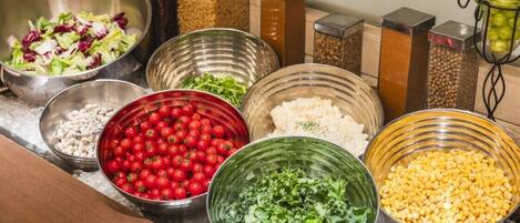A variety of food items in metal bowls on a marble countertop.