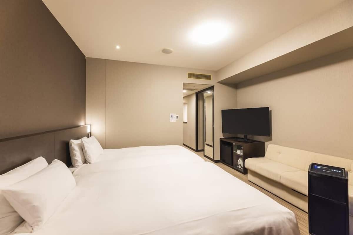 Une chambre d’hôtel avec un grand lit, une télévision, un canapé et un bureau avec un ordinateur.