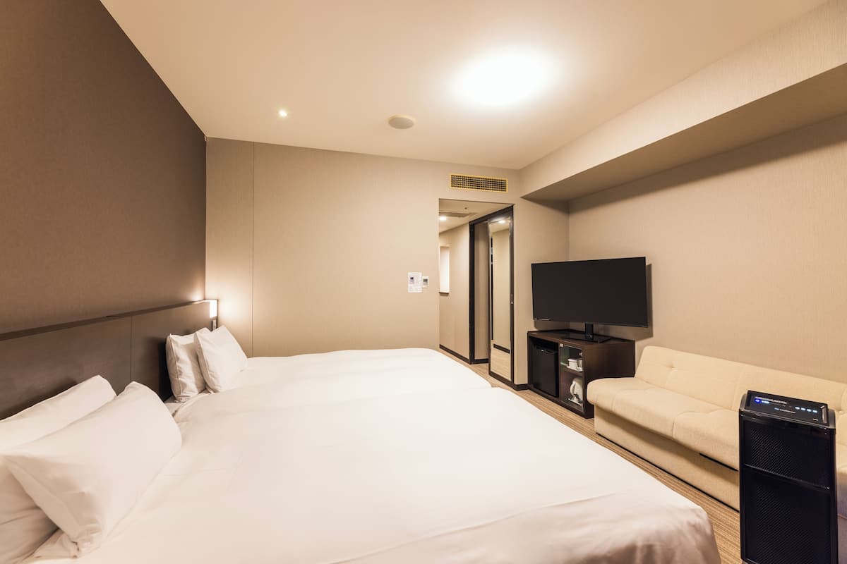 Une chambre d’hôtel avec un grand lit, une télévision, un canapé et une petite table.