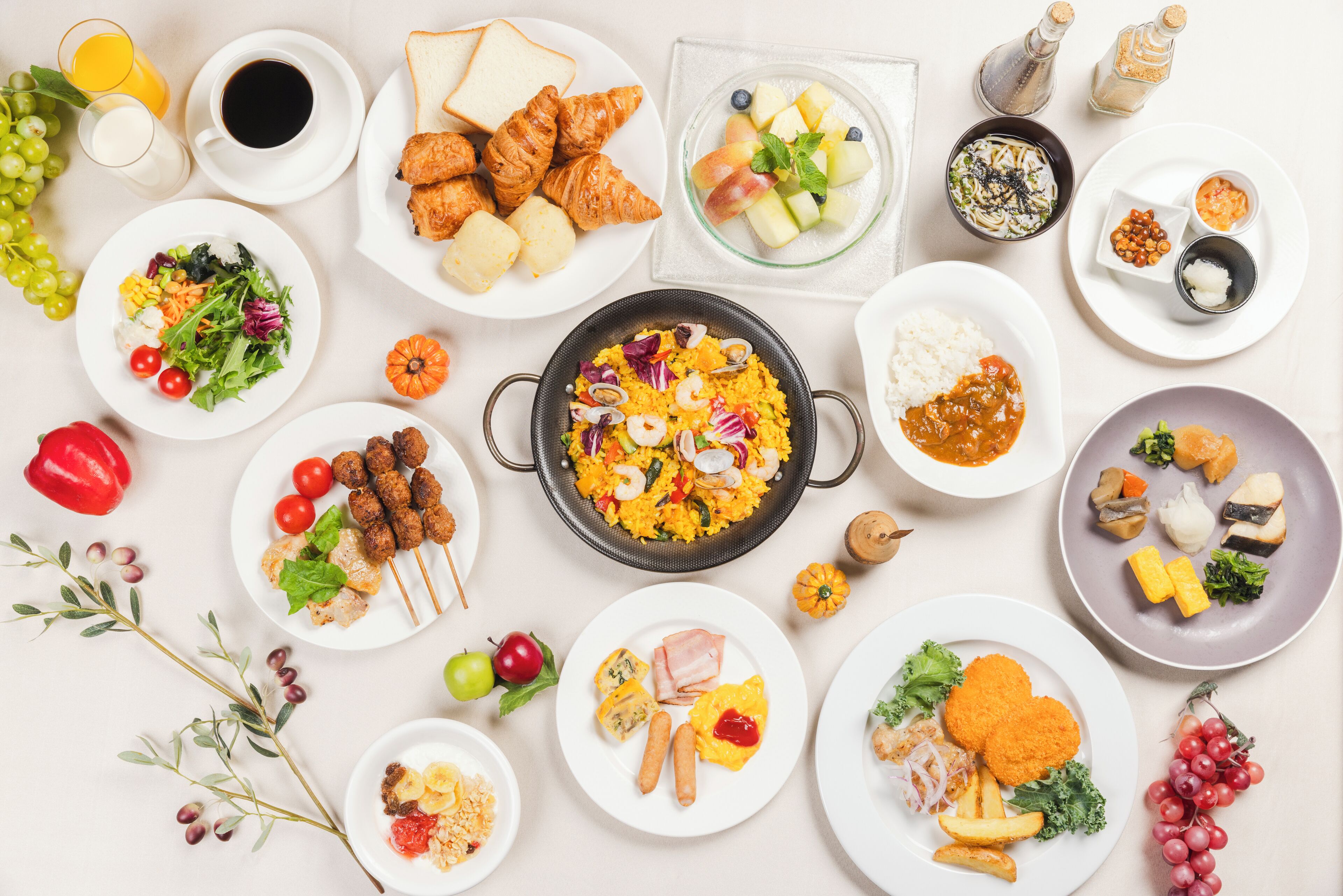 Una variedad de platos que incluyen croissants, una ensalada y un recipiente con arroz y verduras.