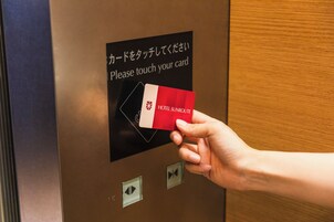 Une main tenant une carte près d’un panneau indiquant qu’il faut toucher la carte.