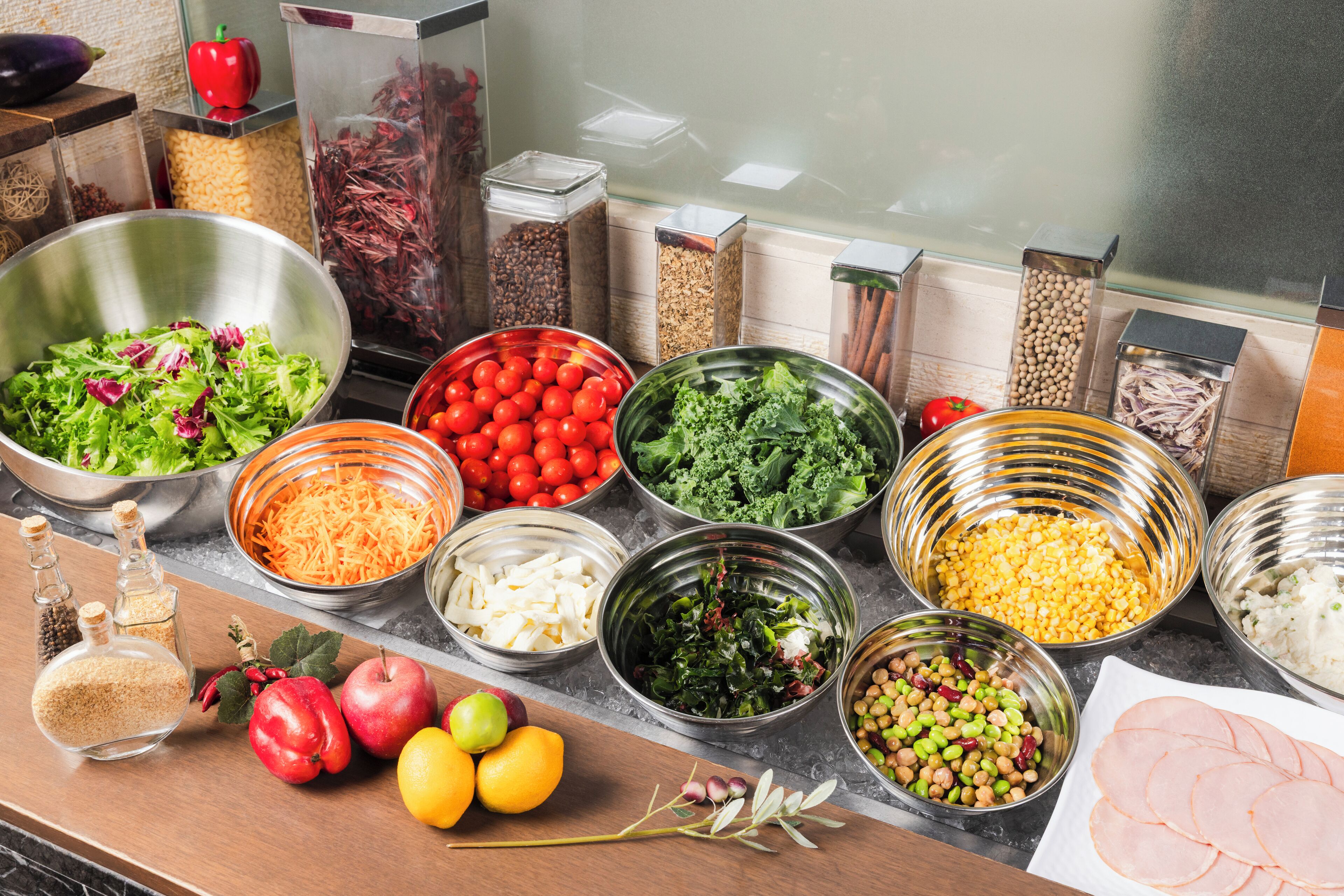 A buffet table with various food items including salads, fruits, and meats.