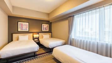 A hotel room with two beds, a check-in desk, and a large window with curtains.