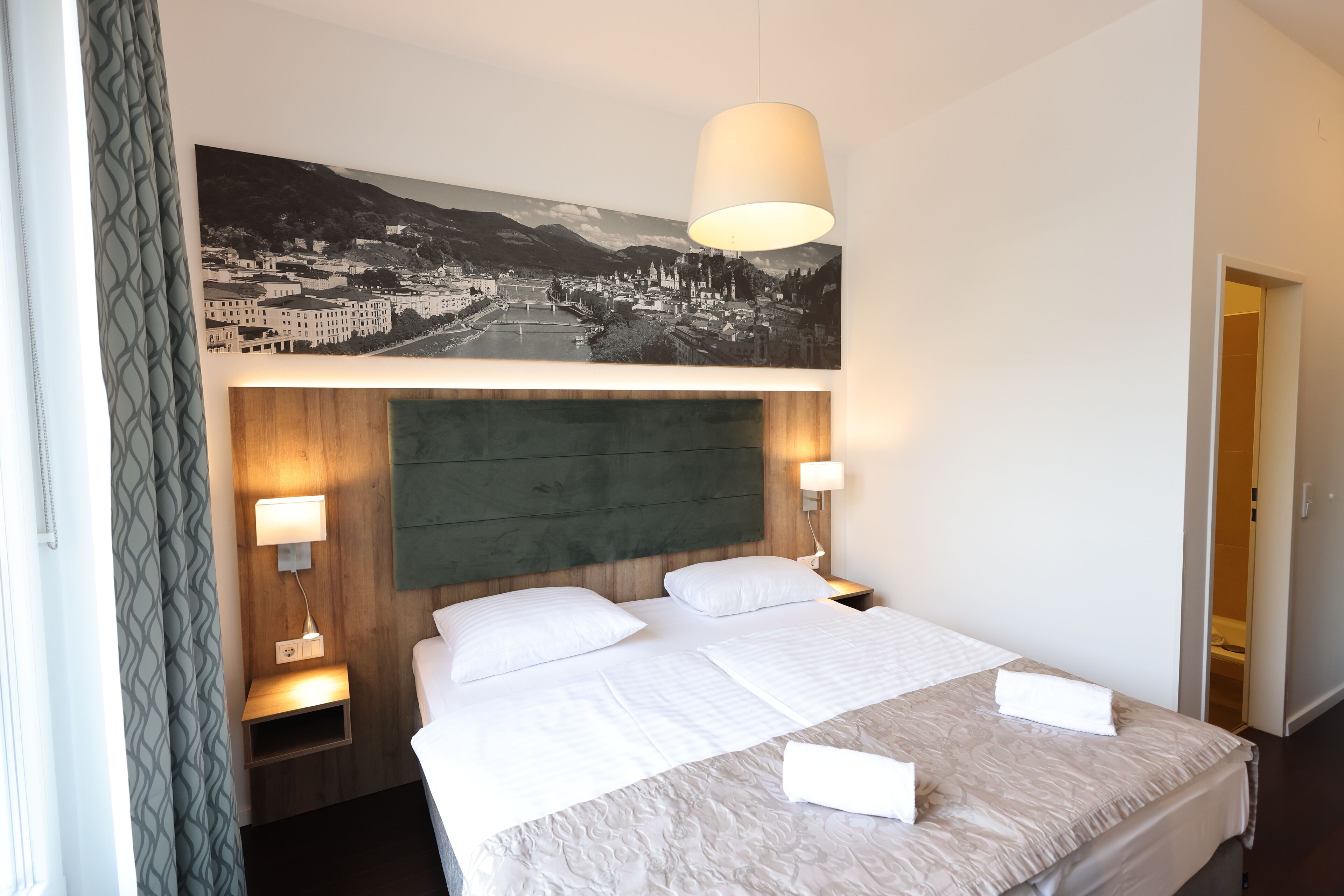 A hotel room with a large bed, two bedside lamps, a headboard, and a wall-mounted picture.