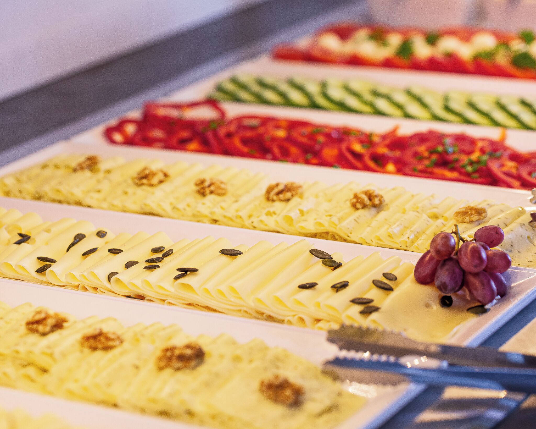 A buffet with various food items including pasta, vegetables, and garnishes.