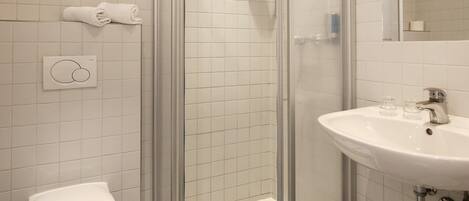 Un baño moderno con ducha de vidrio, inodoro blanco y lavabo con espejo.