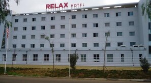 Un edificio de varios pisos con el letrero "RELAX HOTEL" en la parte superior.