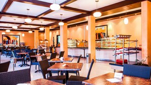 Un restaurante con mesas y sillas, una barra con exhibiciones de comida y un cuadro en la pared.
